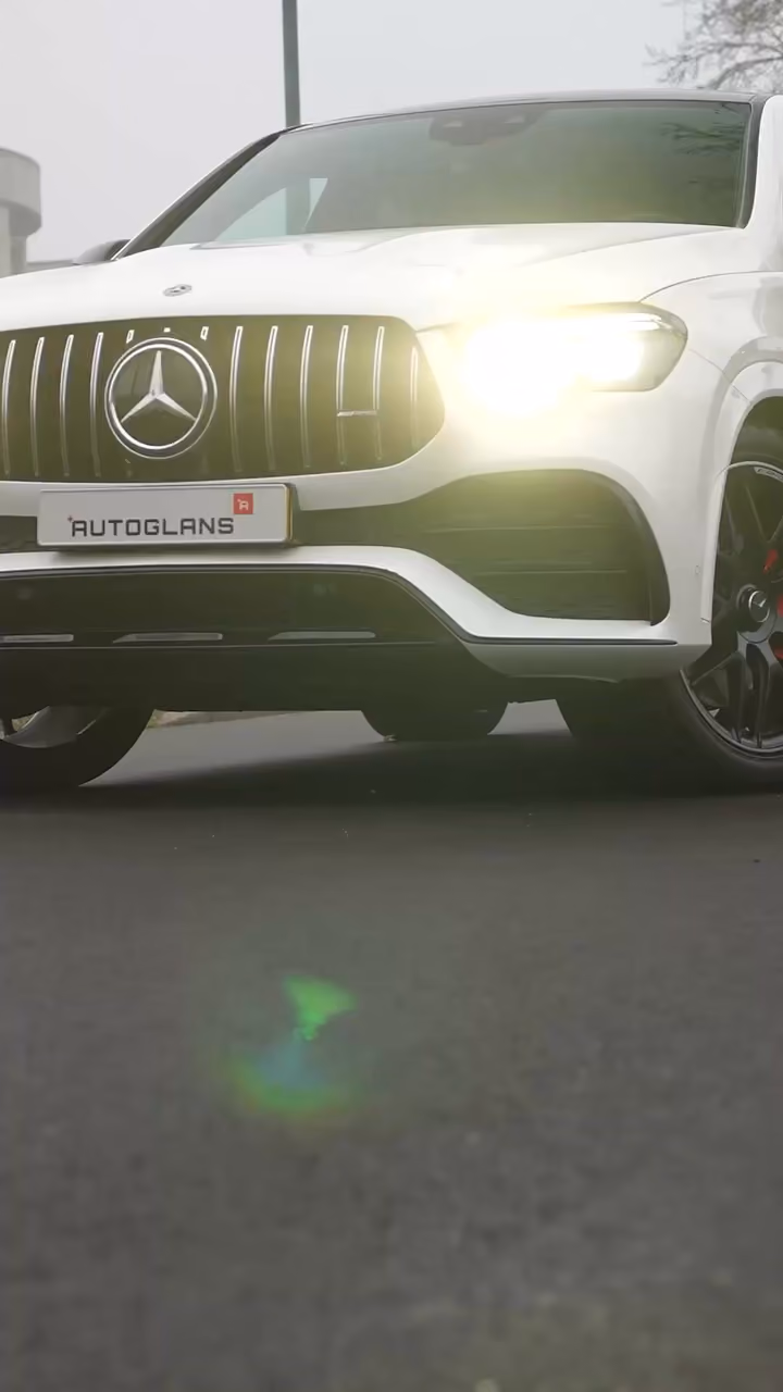 Witte Mercedes AMG met AutoGlans-kenteken en brandende koplampen