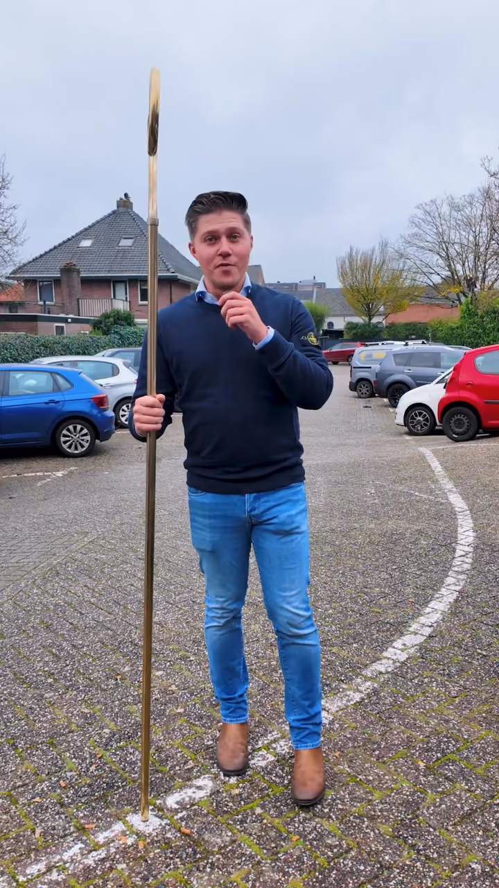 Man met de staf van Sinterklaas op een parkeerplaats